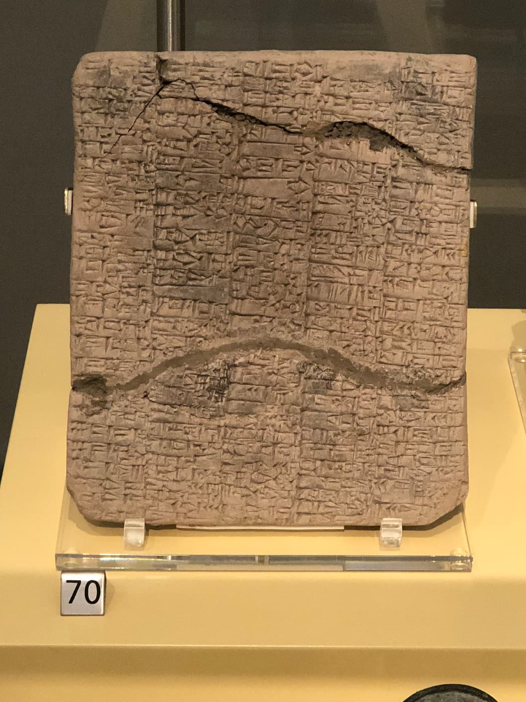 A clay tablet covered edge to edge in cuneiform, cracked across the middle.